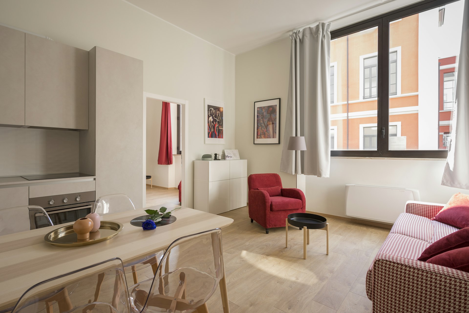 Bright modern studio apartment with red accent chair and minimalist dining area
